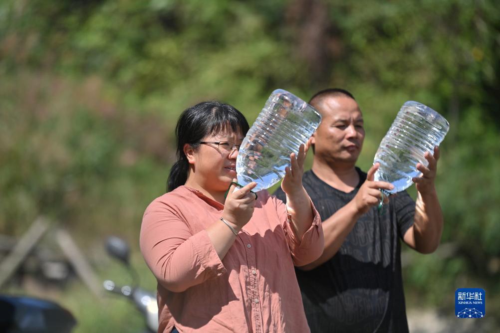 楊寧（左）在查看村民剛剛采集的水樣，為山泉水引水工程做準備（10月8日攝）。新華社記者 黃孝邦 攝